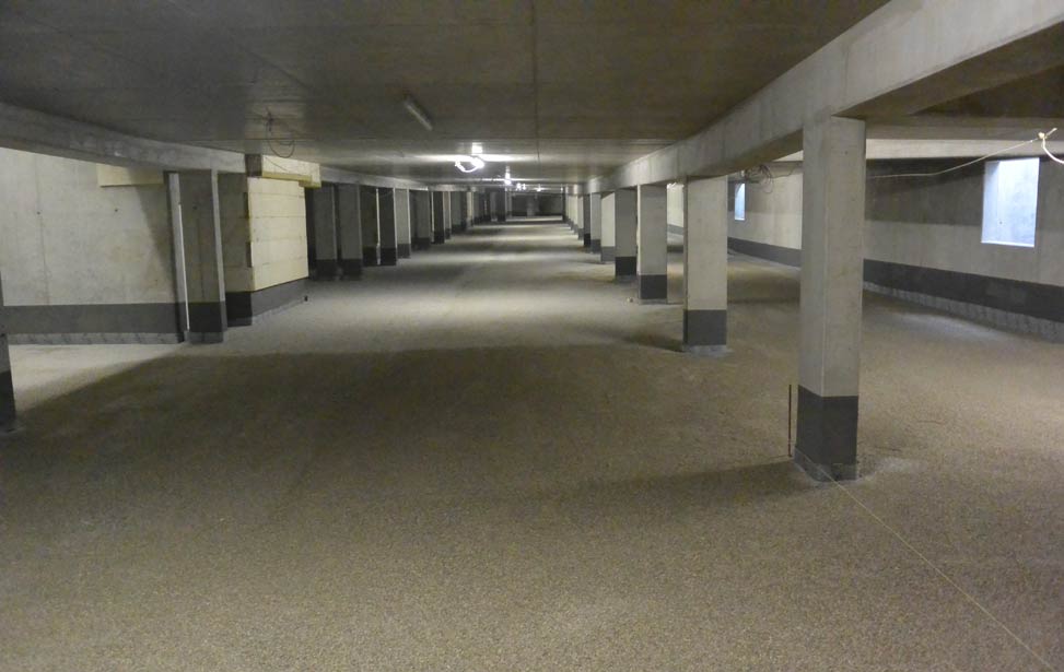 Hier wird eine Ausgleichsschicht als Pflasterbett in einer Tiefgarage mit unserem Flächenfertiger eingebaut.