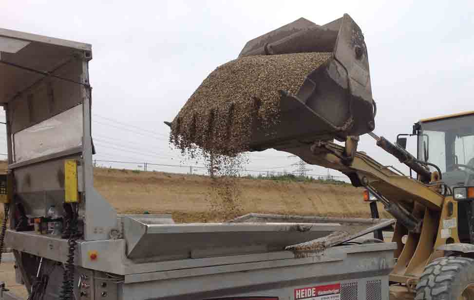 Auffüllen des Materialvorrats beim Flächenfertiger. Hier, in diesem Fall, wird der Bunker mit Kies befüllt.